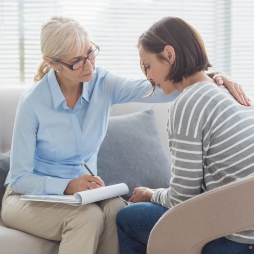 Therapist comforting woman on sofa at home